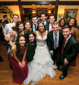 A bride poses surrounded by wedding guests.